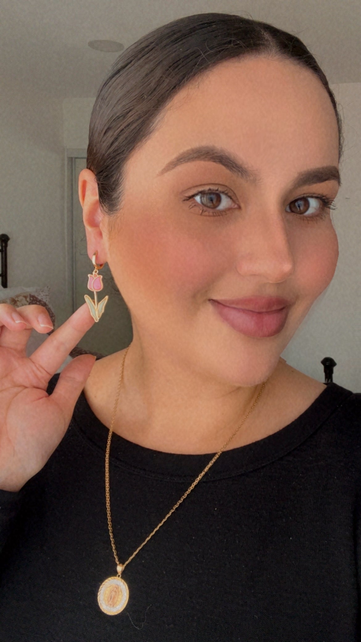 Woman wearing a gold necklace and pink tulip earrings.