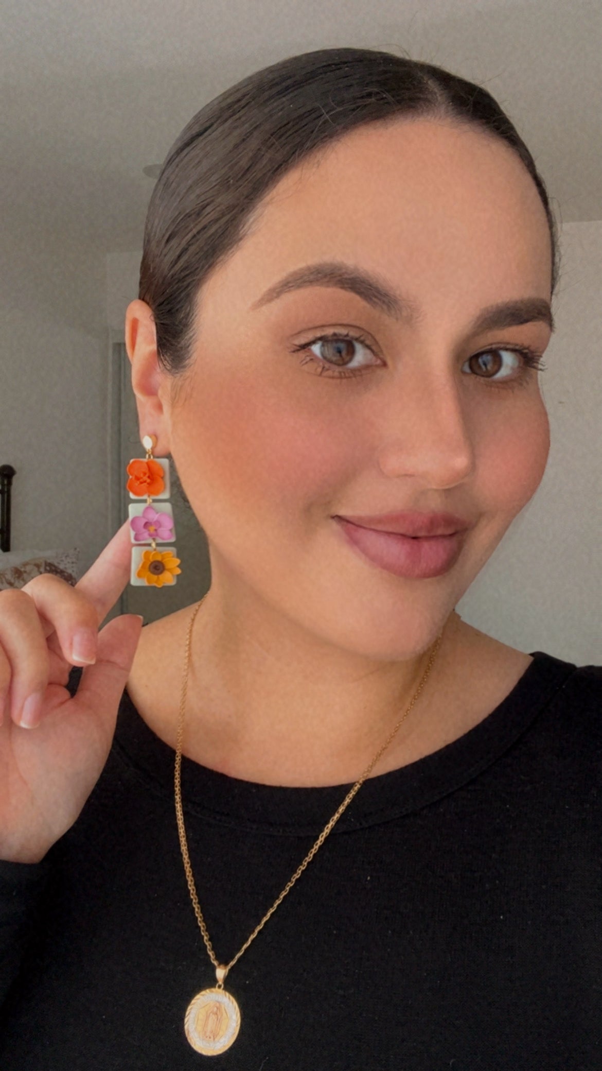 Woman wearing colorful flower earrings with a neutral background