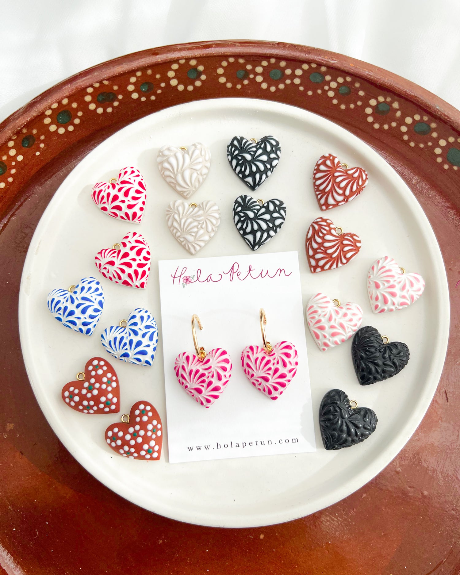 Heart-shaped earrings on a display card with a decorative plate underneath