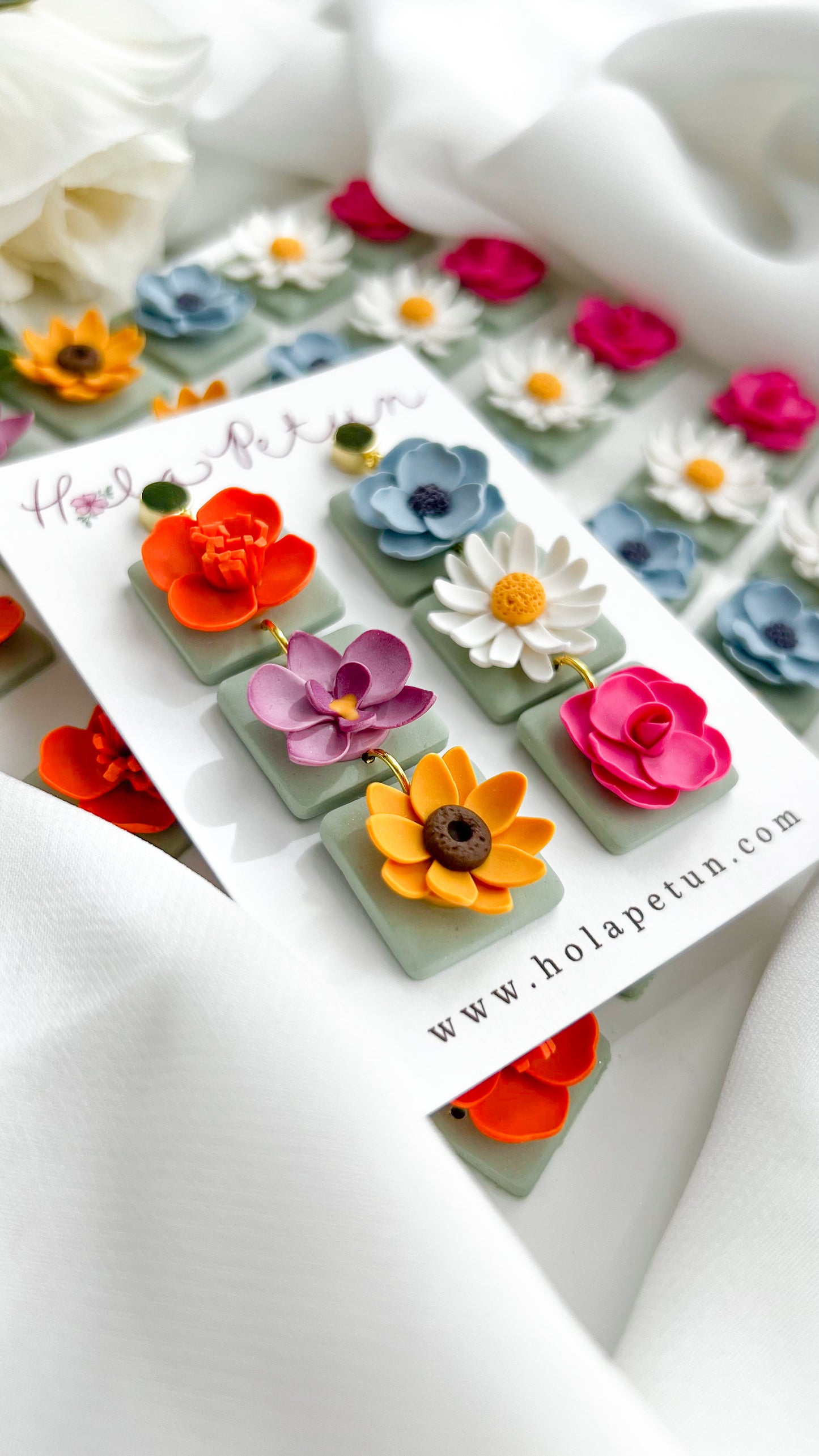 Colorful flower-shaped earrings on a card with 'Hola Petun' branding.