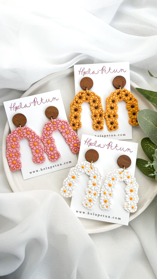 Three pairs of earrings on their respective cards with 'Hola Petun' branding on a white fabric background.